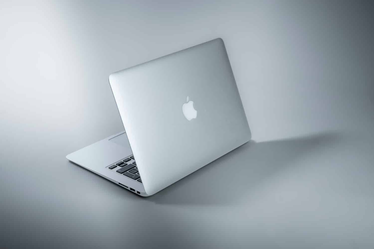 Silbernes aufgeklapptes MacBook vor grauem Hintergrund