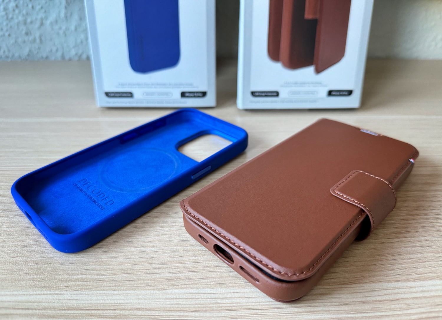 Decoded Cases aus braunem Leder und blauem Silikon mit Verpackung auf einem Schreibtisch