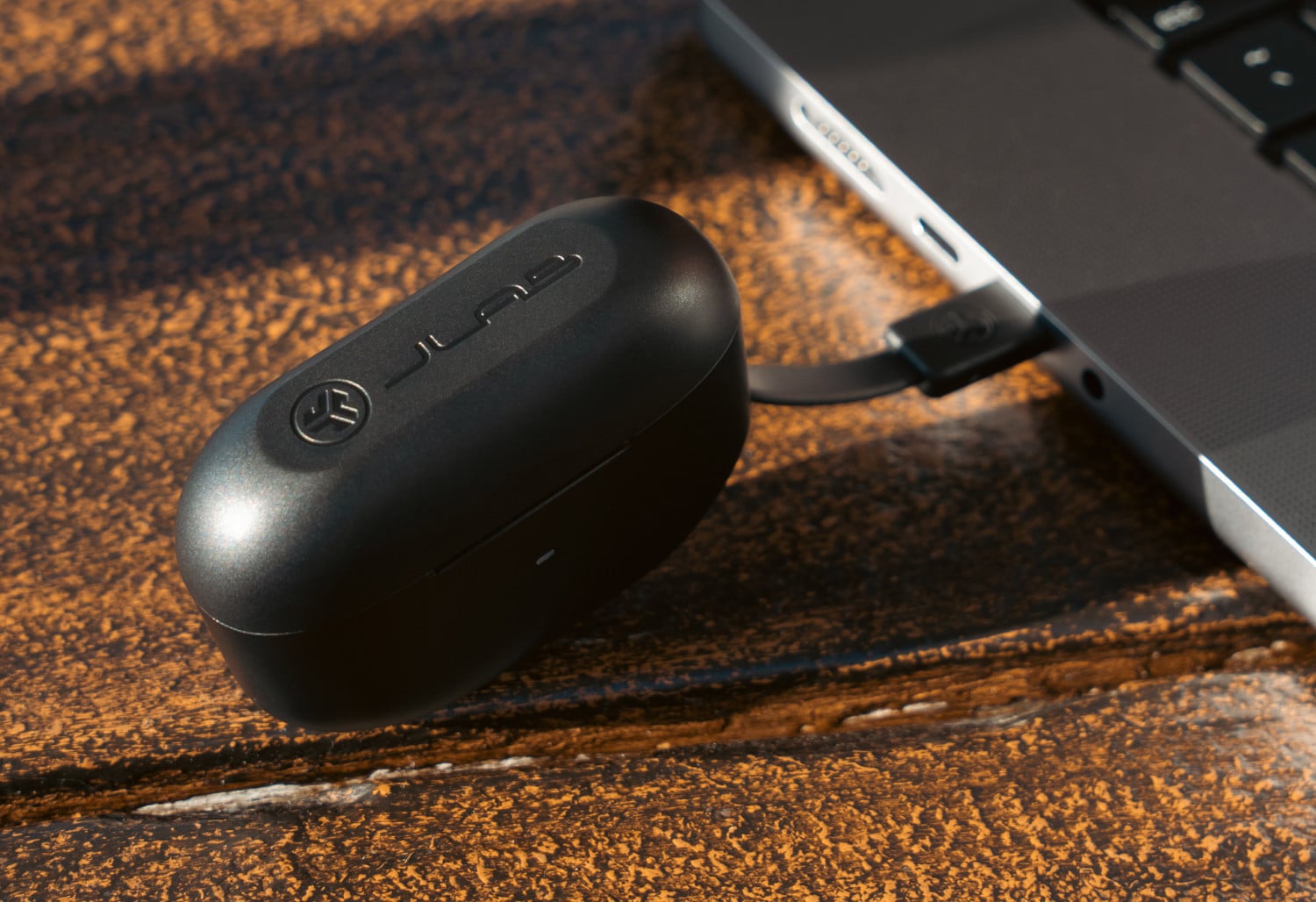 Ladecase der JLab JBuds ANC 3 wird mit integriertem USB-C-Kabel an einem MacBook aufgeladen