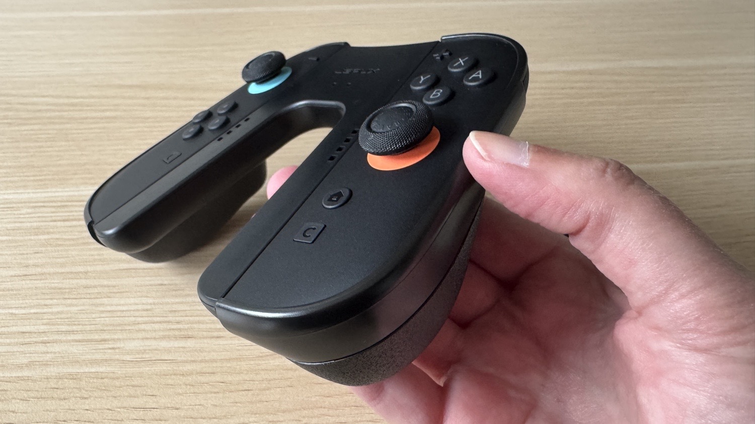 Eine Hand hält den JSAUX JoyVerse Dual Grip in die Kamera
