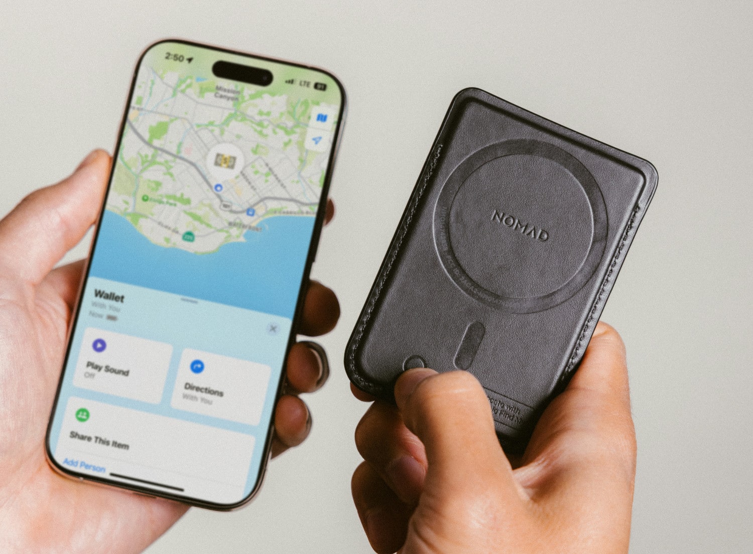 Nomad Leather Mag Wallet in Schwarz neben einem iPhone mit Wo Ist?-App